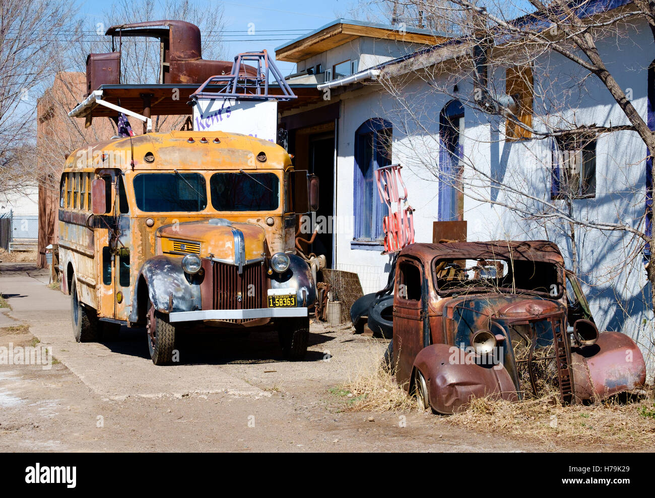 Old rusting yellow school bus and Chevy Pickup on the forecourt of Kent's Exhaust Shop in Alamosa, Colorado, USA Stock Photo