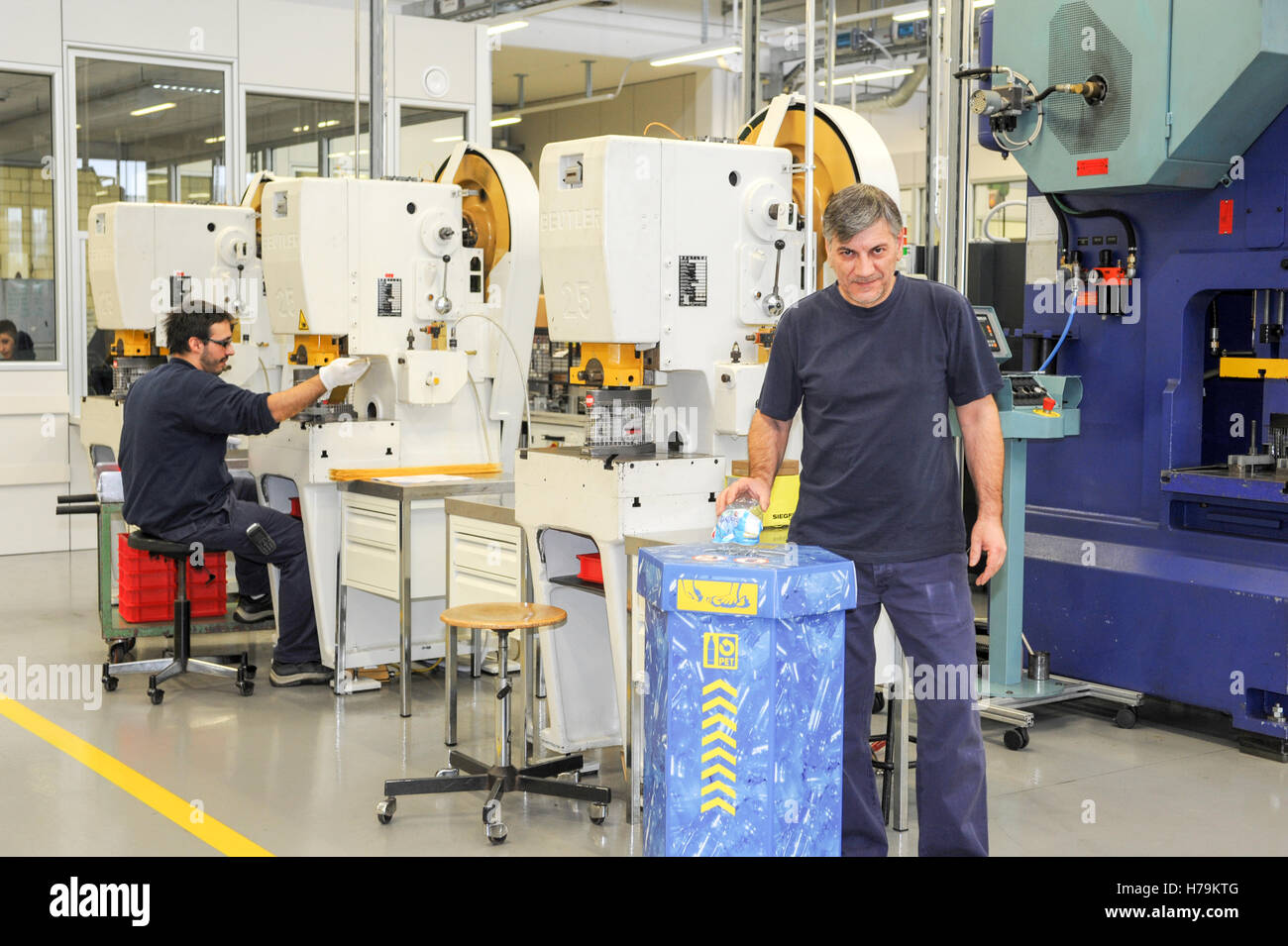 Chiasso, Switzerland - 13 January 2014: man who is recycling a bottle of pet into the appropriate container in the industry hall Stock Photo