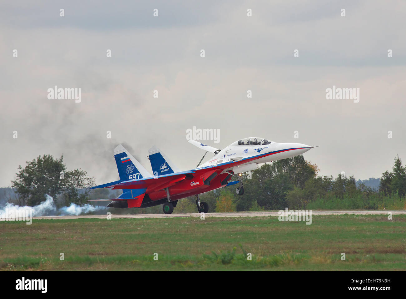 Kiev Region, Ukraine - October 2, 2010: Sukhoi Su-30LL fighter plane in Russian flag colors is landing with smoke on the runway Stock Photo