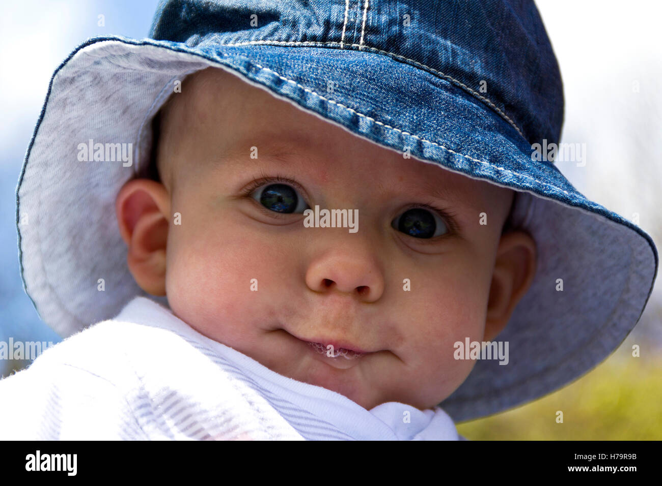 Baby boy dribbling and wearing a sun hat Stock Photo