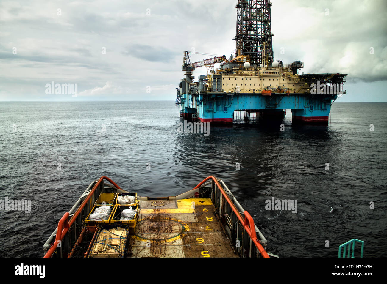 Anchor-handling Tug/Supply (AHTS) vessel during dynamic positioning (DP) operations near Oil Rig. Stock Photo