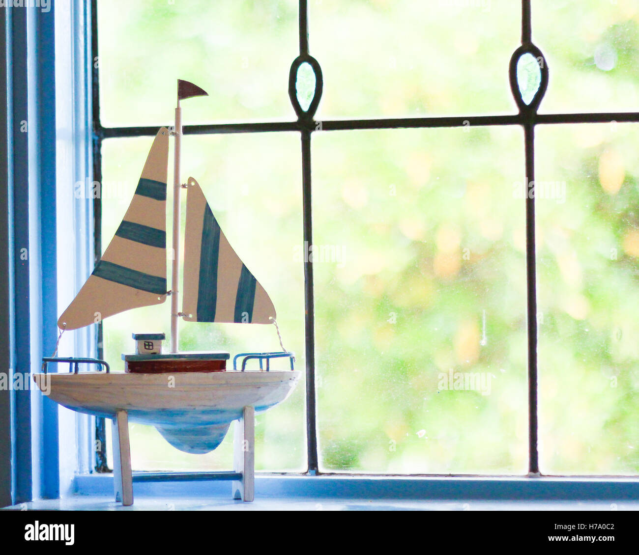 Sailboat ornament in front of lead light window in beach house Stock Photo
