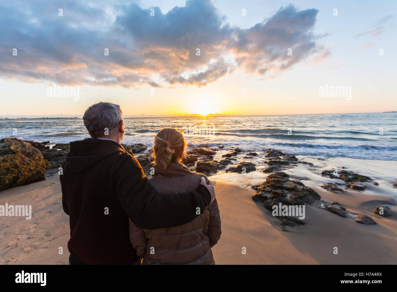 Couple in love watching a sunset on the beach hi-res stock photography ...