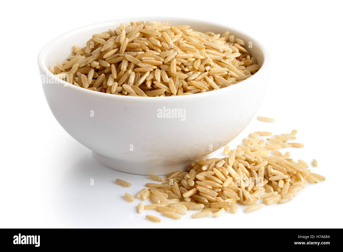 Bowl of long grain brown rice isolated on white. Spilled rice. Stock Photo