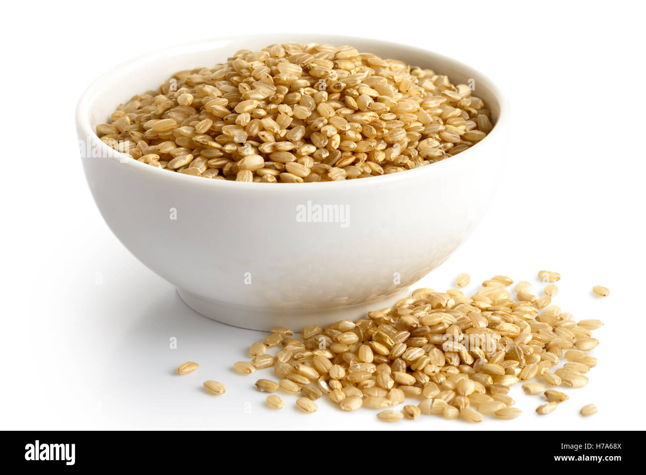 Bowl of short grain brown rice isolated on white. Spilled rice. Stock Photo