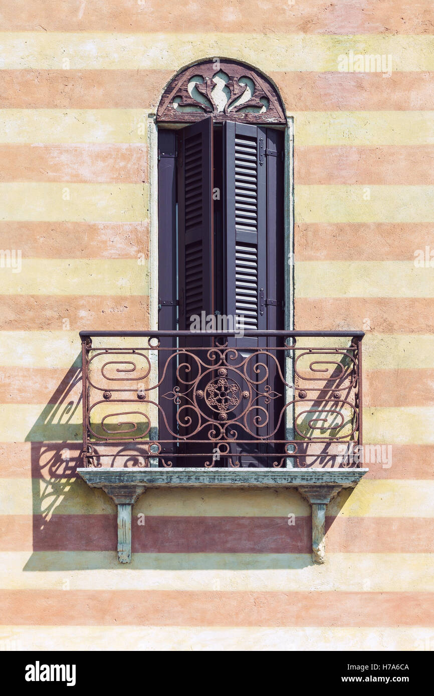 Typical Italian balcony with decorative railing and closed window shutters Stock Photo