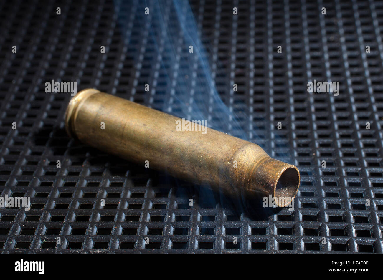Empty rifle cartridge on a grate that has smoke nearby Stock Photo Alamy