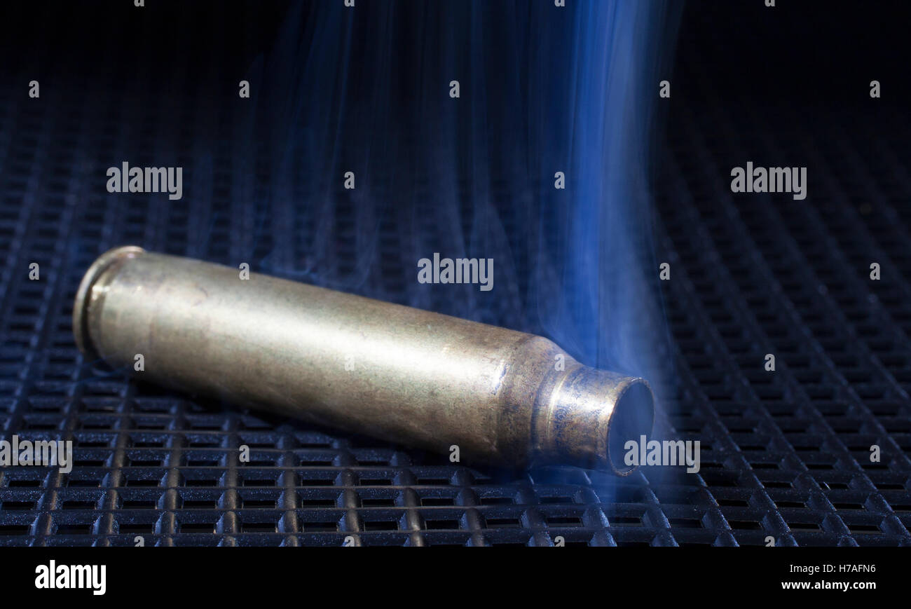 Rifle brass on a black grate that is smoking hot Stock Photo