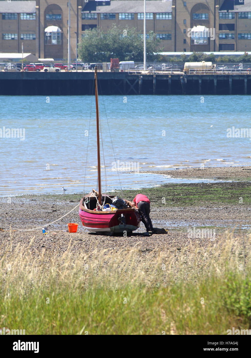 Man working on maintaining red fishing boat at Weston Shore, Woolston, Southampton, Hampshire UK Stock Photo
