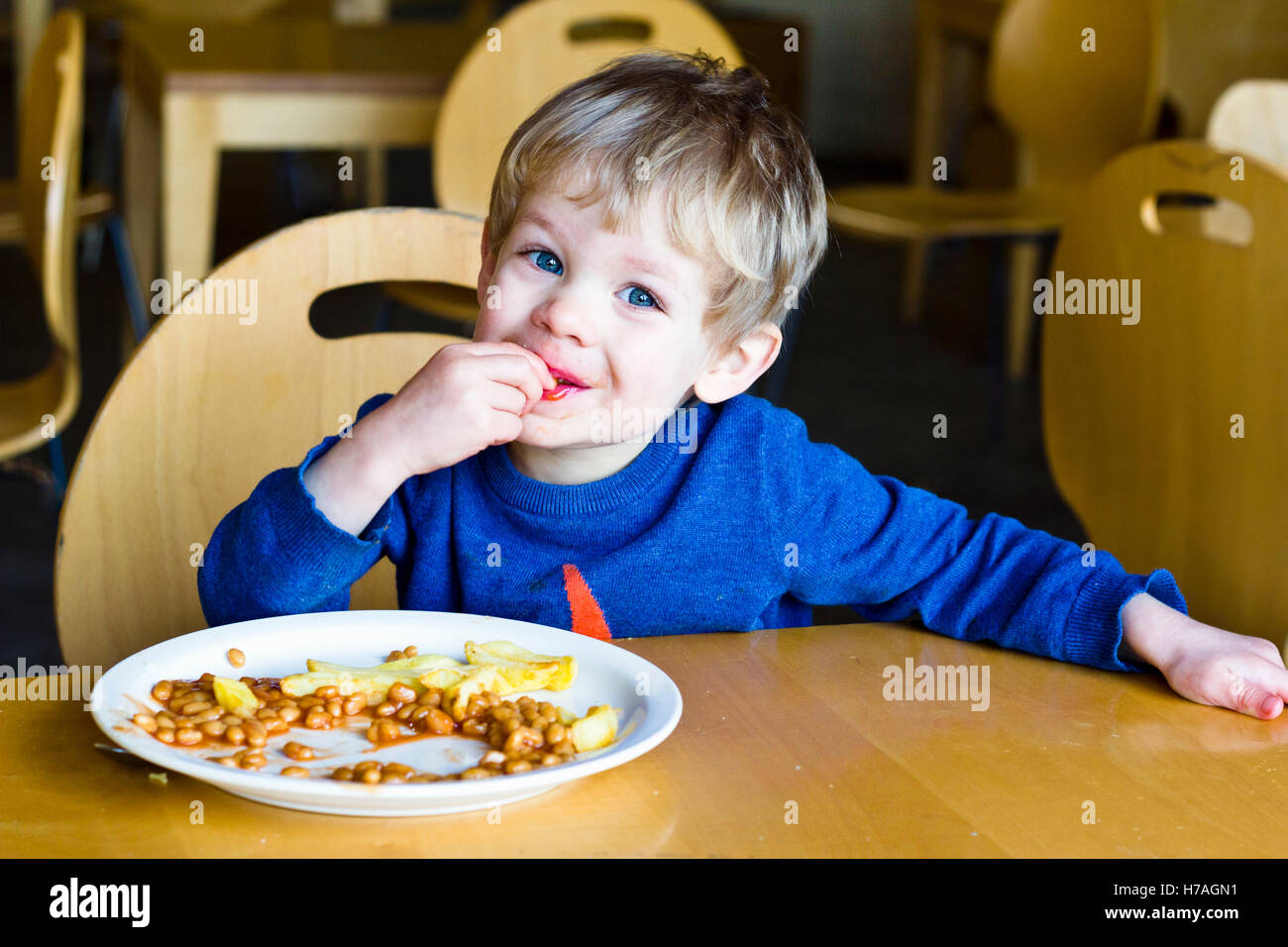 Young boy eating chips and baked beans in a restaurant Stock Photo