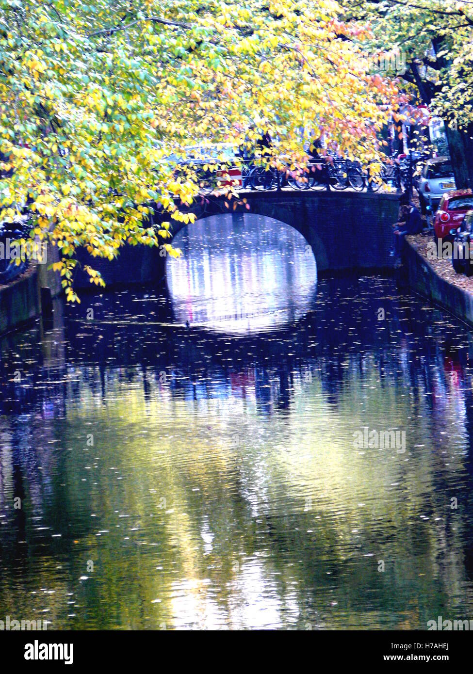 Bridge and trees reflected on still water on a Amsterdam canal in autumn. Perfect shot for travel blogs, ads, and marketing adventure products Stock Photo