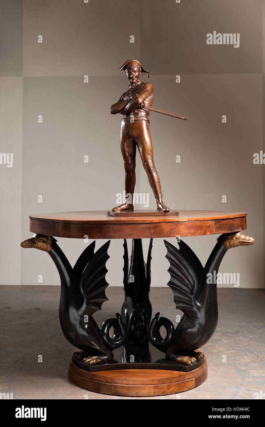 Cast bronze of L'Arlequin on top of a walnut centre table supported by three ebonised and gilt wood dragons Guinevere's antique Stock Photo