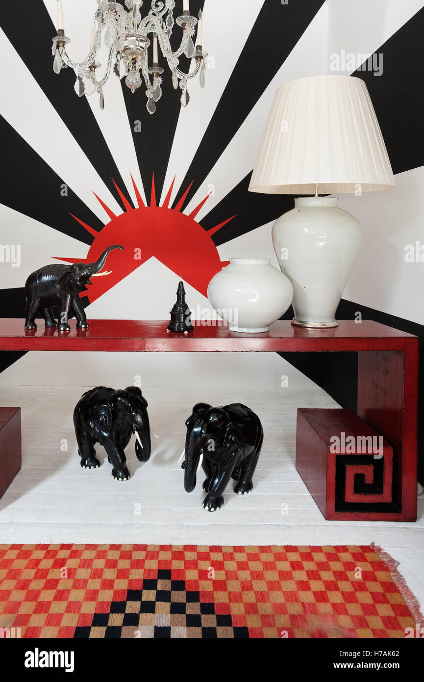 Carved ebony elephants beneath a Chinese red lacquer geometric scroll foot altar table.  Guinevere's antique shop on Kings Road, Stock Photo