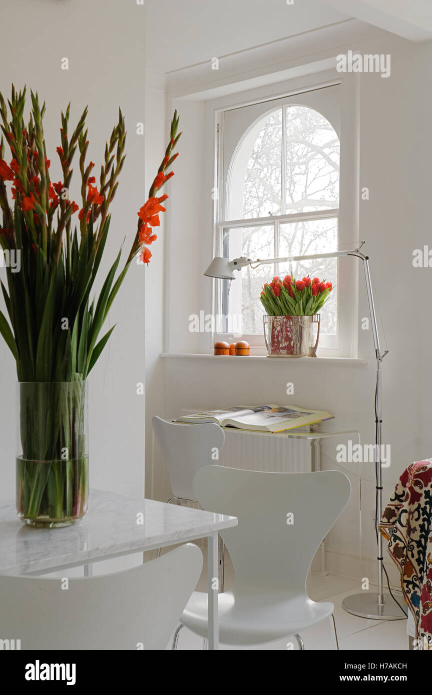 Cut flowers and white seating with arched window in living room of London home, England, UK Stock Photo