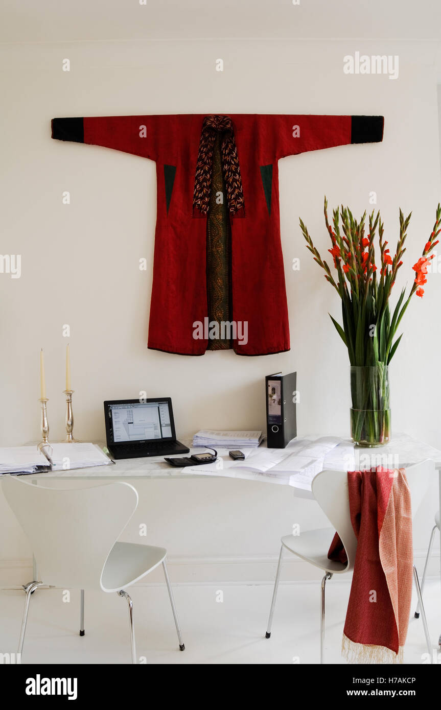 Red wall-mounted coat above desk with cut flowers in work space of London home, England, UK Stock Photo