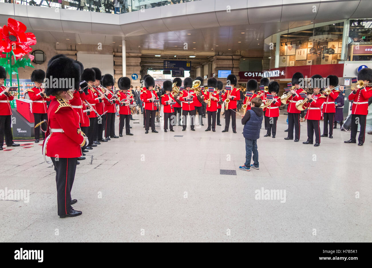 Waterloo Station, London, UK.  3rd November, 2016. The band of the Grenadier Guards performs for commuters and passengers on the concourse of Waterloo Station, London, UK while a young boy acts as conductor. Their performance was in support of  the annual Royal British Legion Poppy Appeal. Credit:  Graham Prentice/Alamy Live News Stock Photo