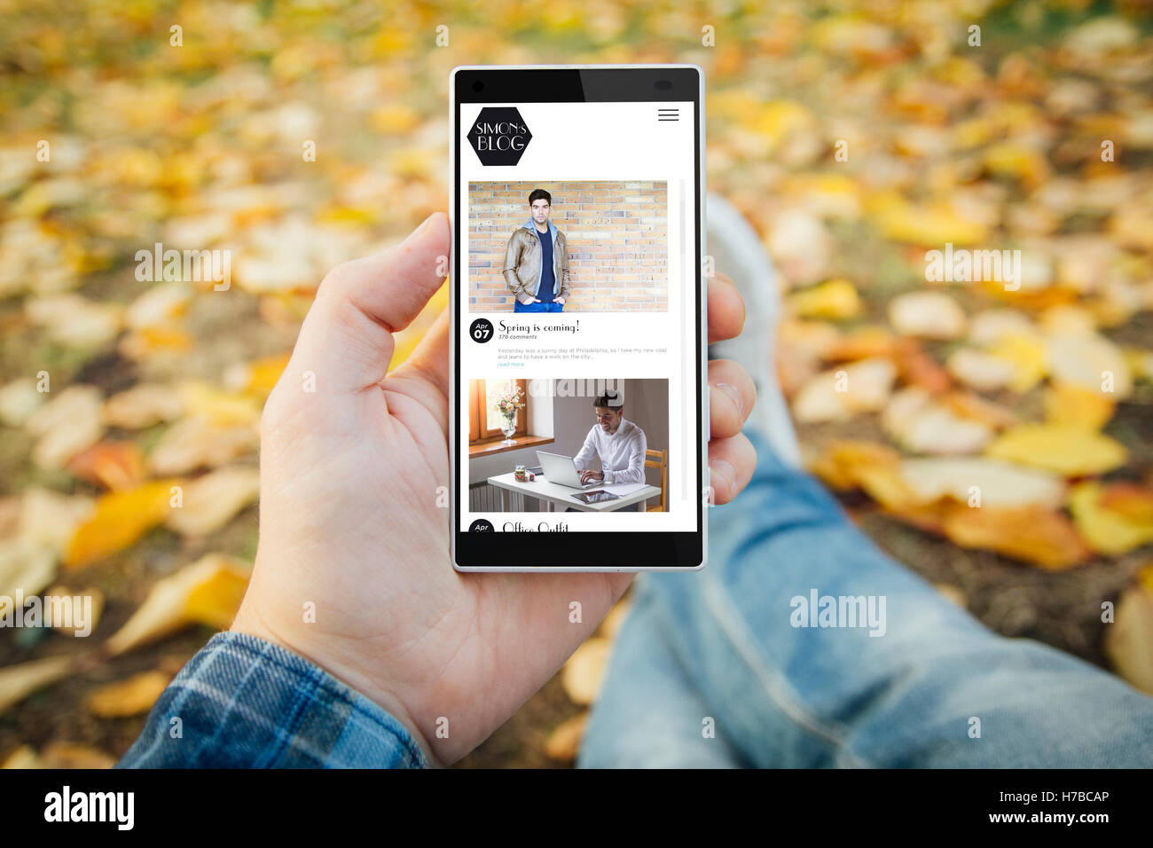 man in the park with blog smartphone. All screen graphics are made up. Stock Photo