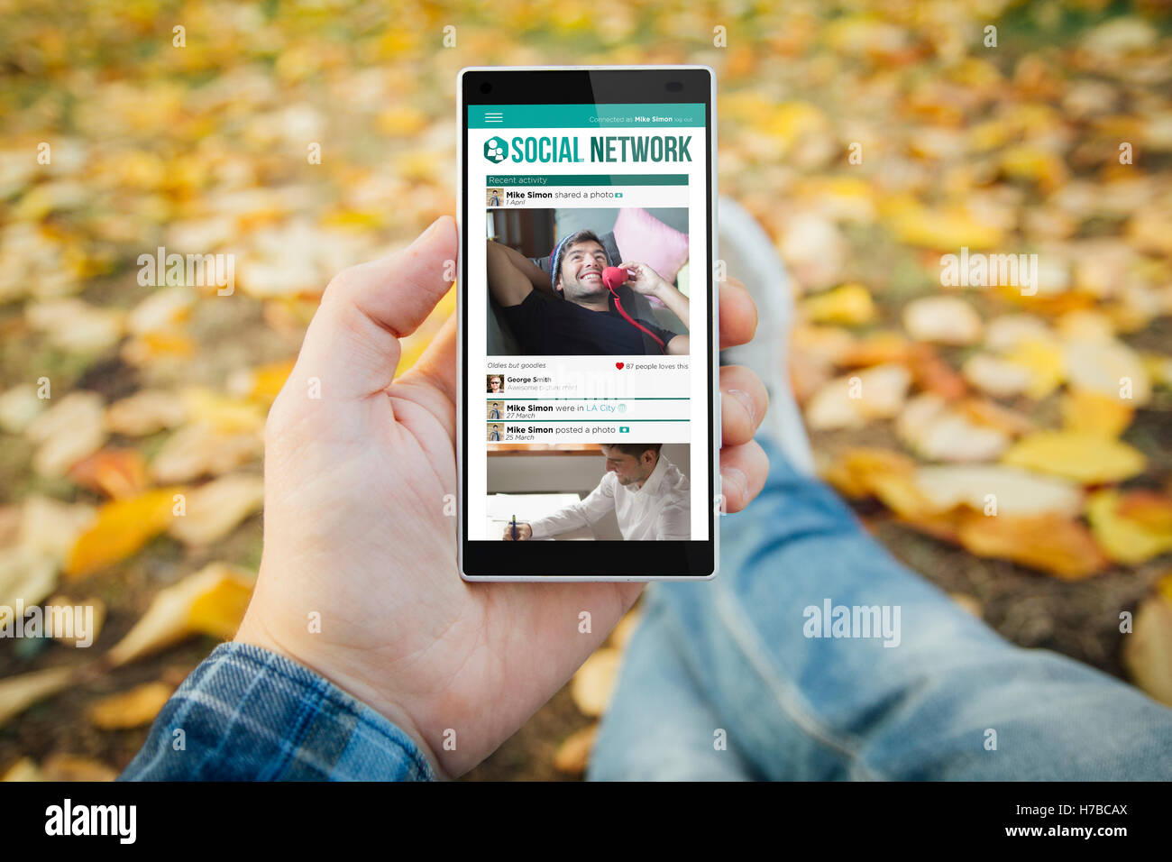 man in the park with social network smartphone. All screen graphics are made up. Stock Photo