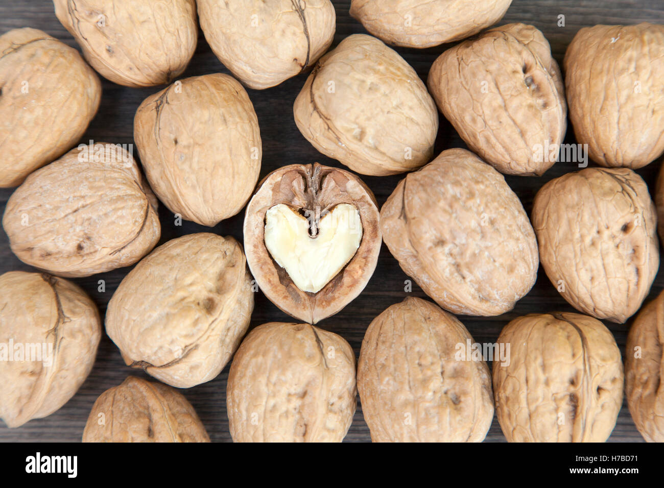 Cracked walnut with a heart shaped interior surrounded by close walnuts