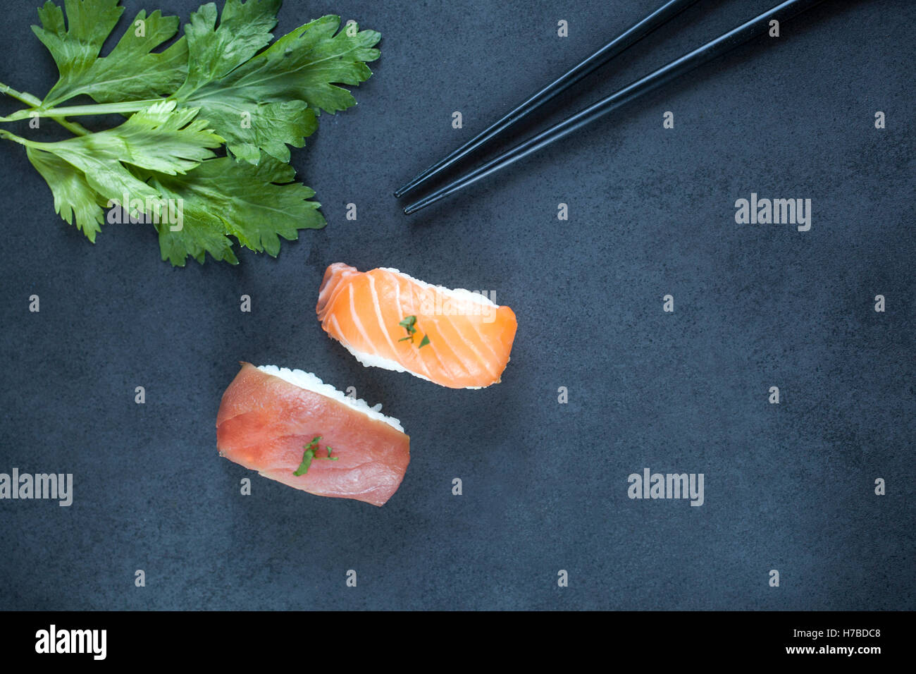 Close-up view of fresh tuna and salmon nigiri and chopsticks on a dark plate Stock Photo