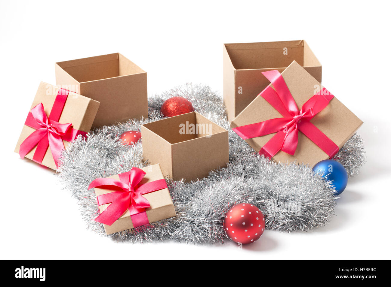 Several Open Christmas gift boxes with red ribbons tree balls and tinsel garland isolated on white. Stock Photo
