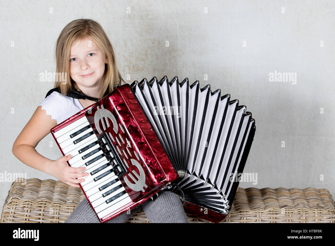 Girl playing an Accordion with a smile on her face Stock Photo