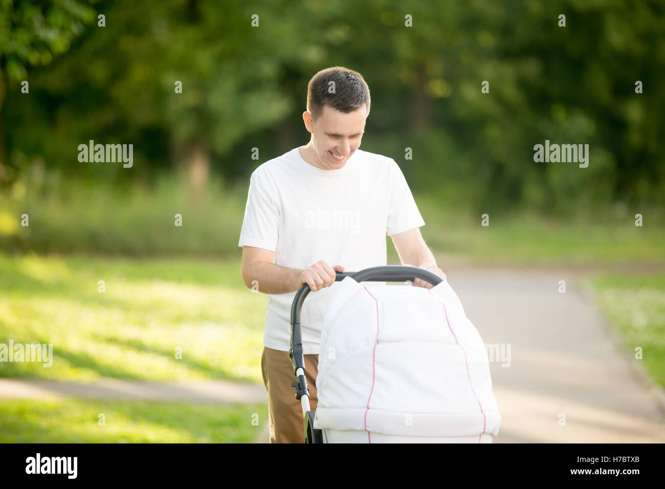 Young father pushing a stroller in park Stock Photo