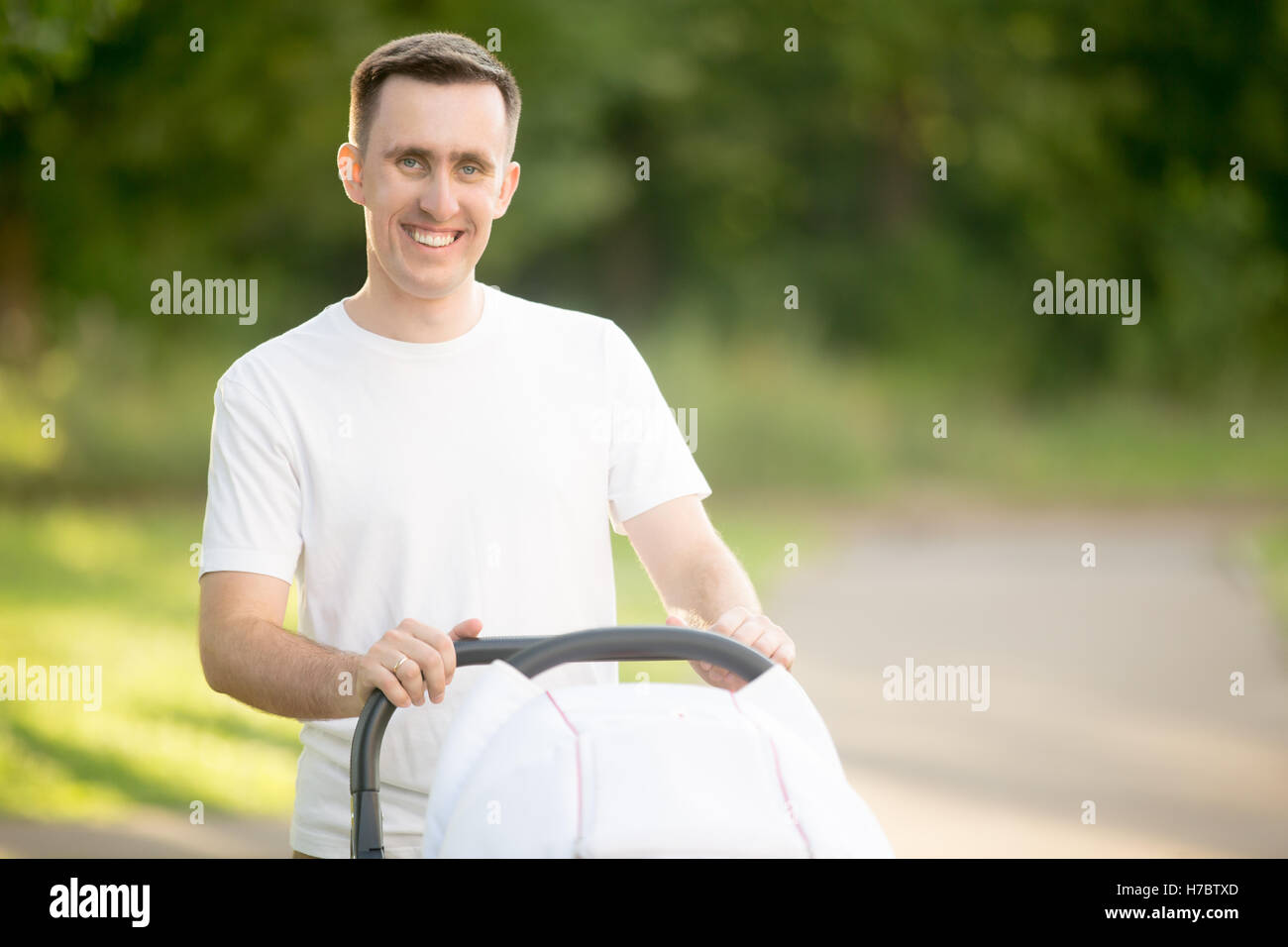 Portrait of happy dad with pram in park Stock Photo
