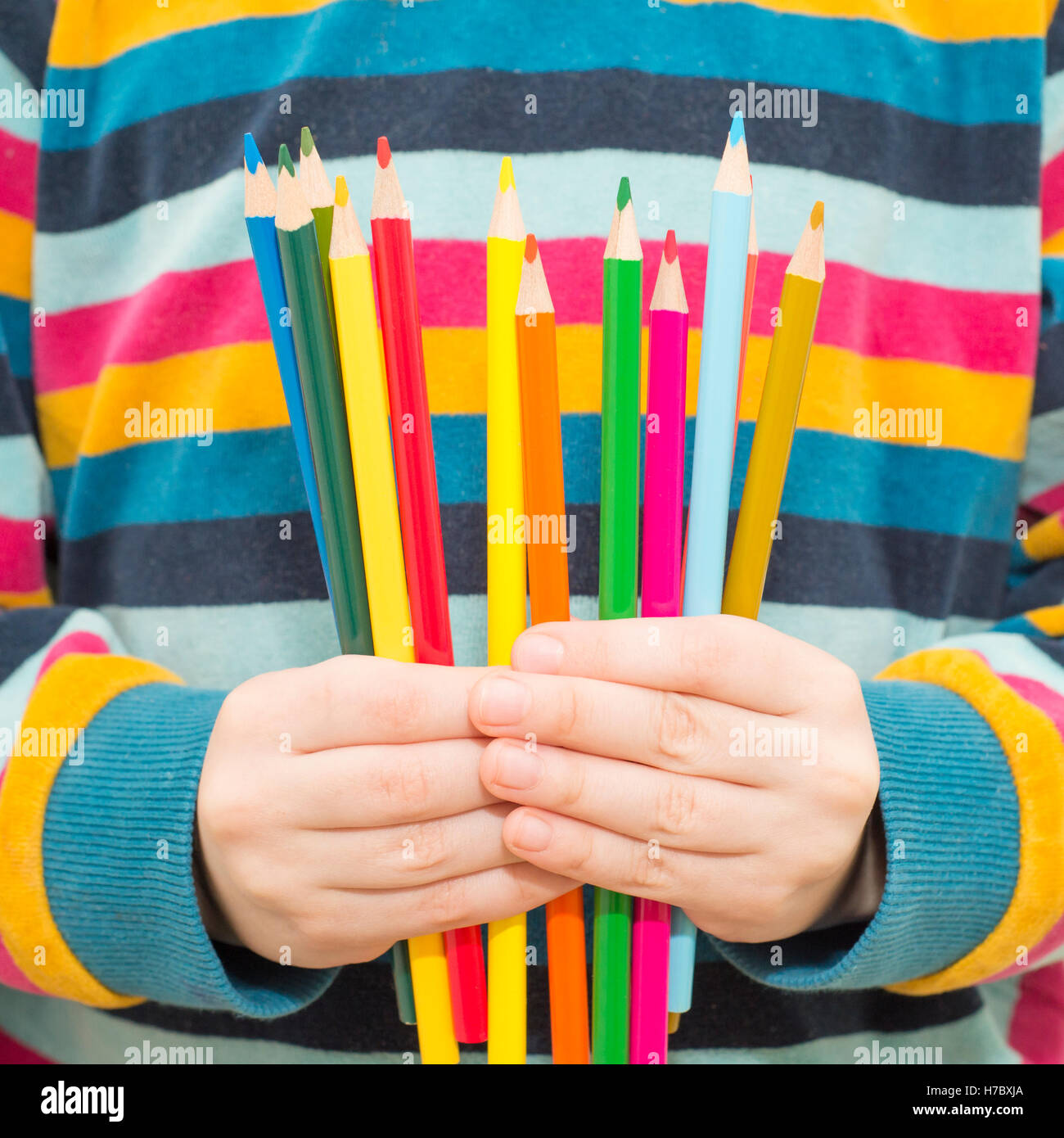 Child hands holding colorful pencils. Concept of childhood creativity, drawing and fun education. Stock Photo