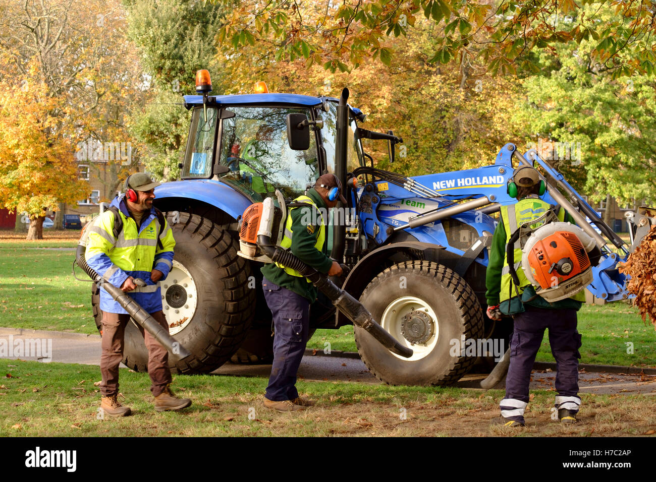Workmen in hi viz using leaf blowers to clear autumn leaves. Victoria Park, East London, 2016 Stock Photo