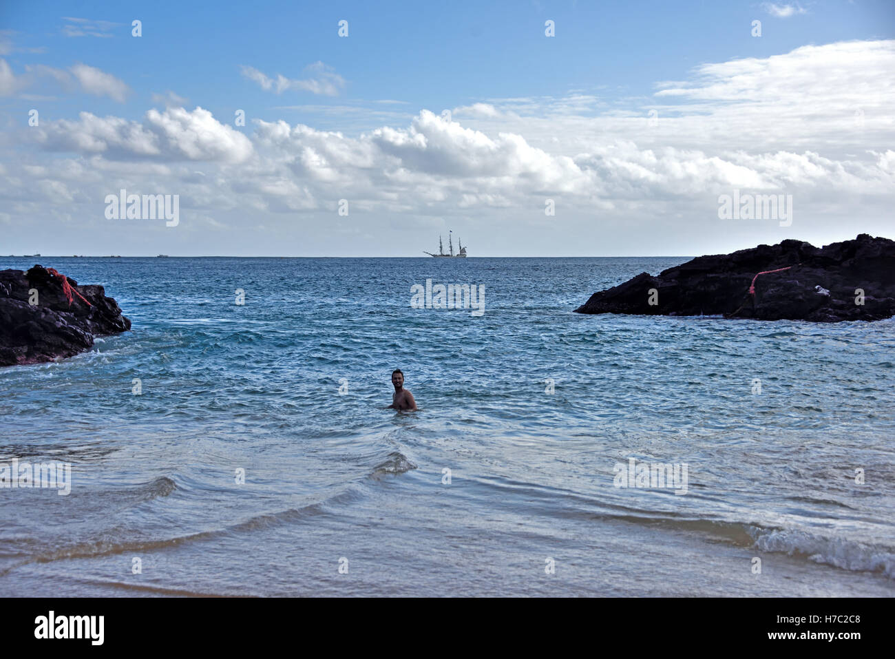 Swimming in Comfortless Cove on the North West coast of Ascension Island. The Tall Ship on the horizon is The Bark Europa. Stock Photo