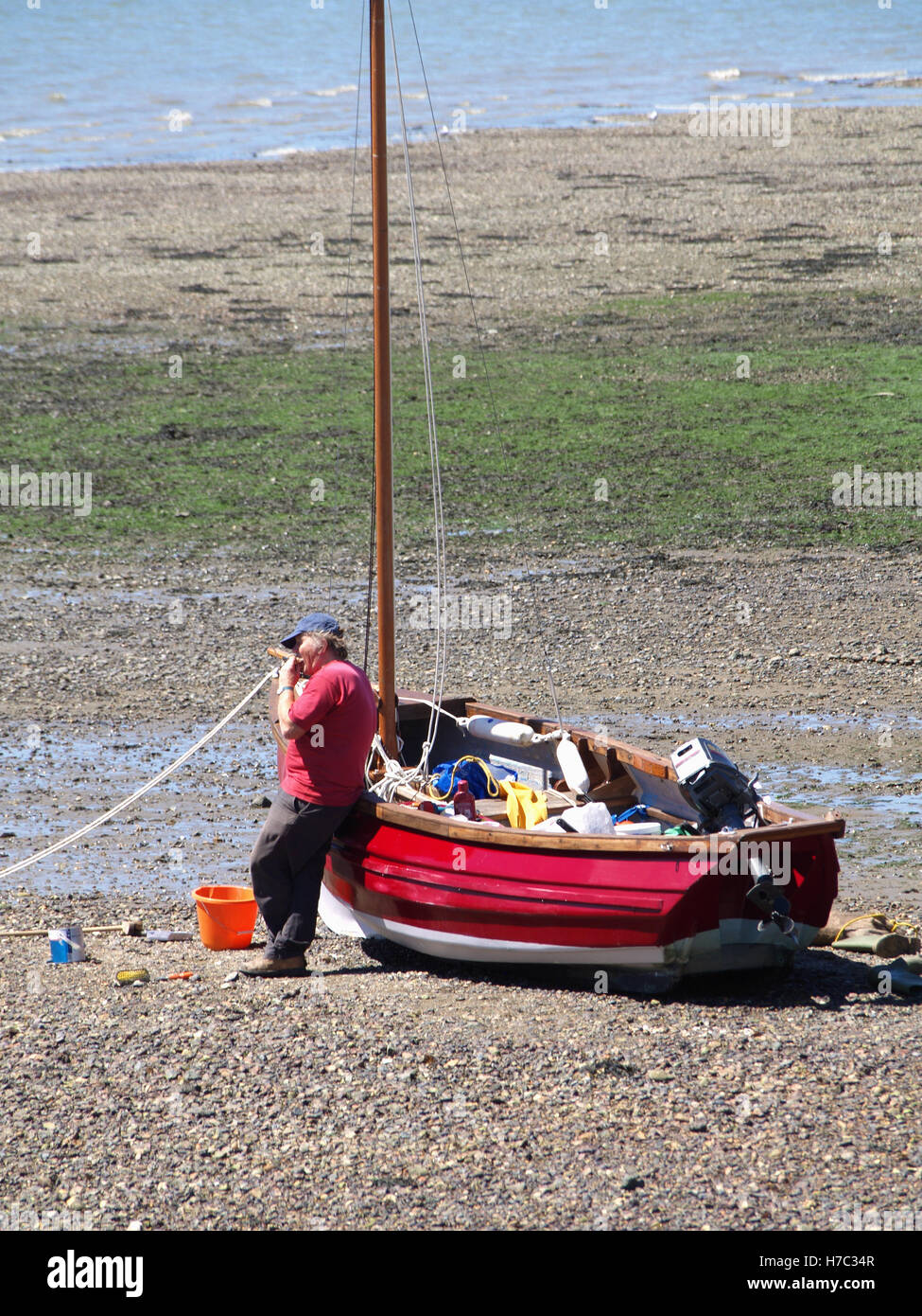 Man working on maintaining red fishing boat at Weston Shore, Woolston, Southampton, Hampshire UK Stock Photo