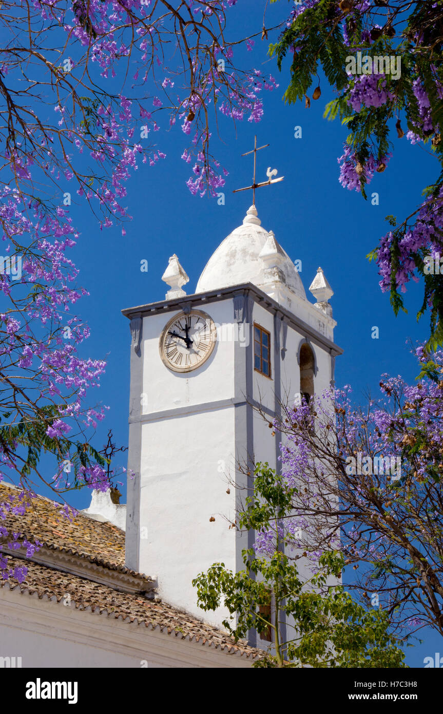 Portugal, the Algarve, Moncarapacho village church clock tower and jacaranda tree in flower Stock Photo