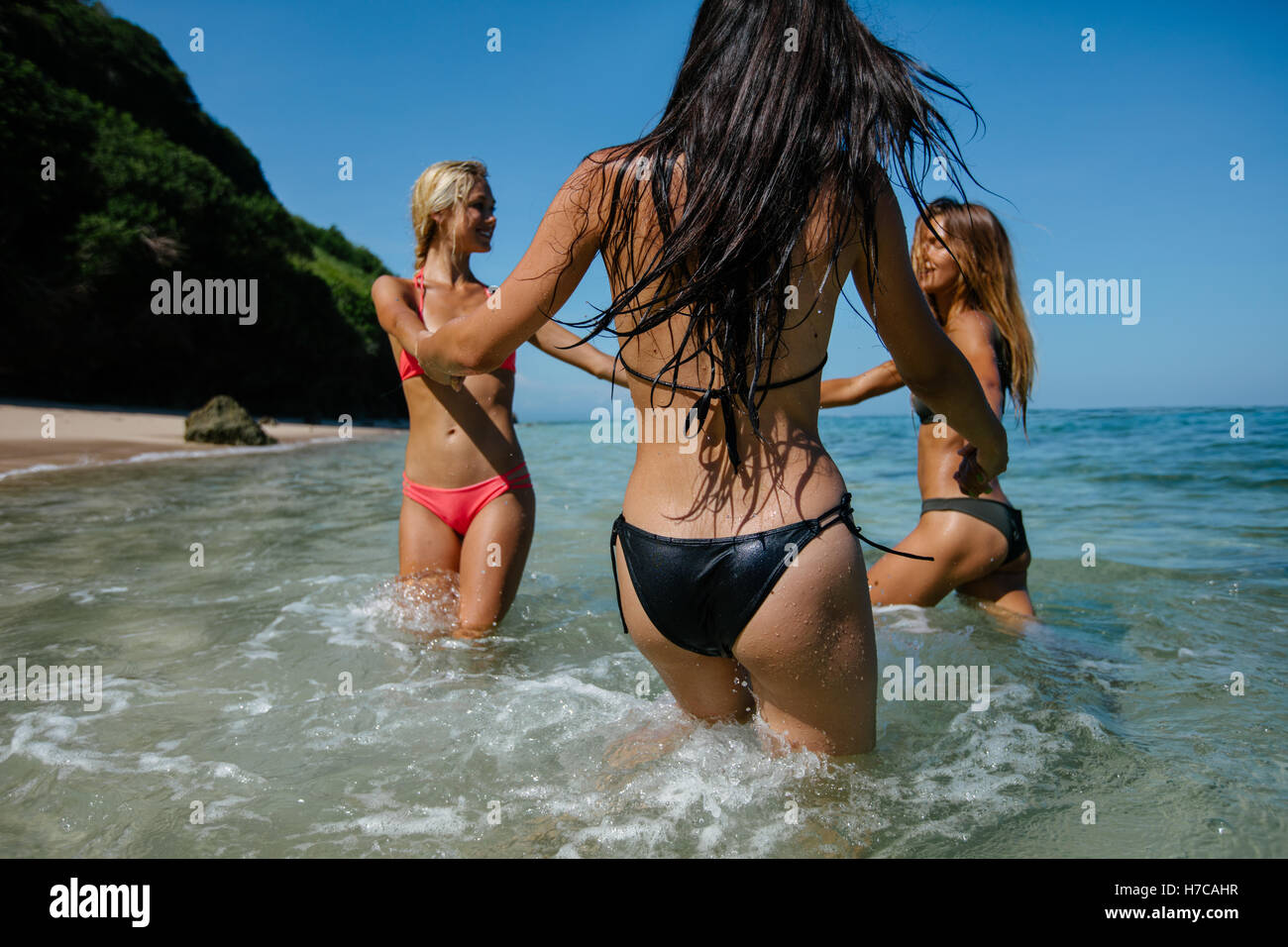 Shot of group of female playing with holding hands on the beach. Women in bikini playing ring around the rosy in sea water. Stock Photo