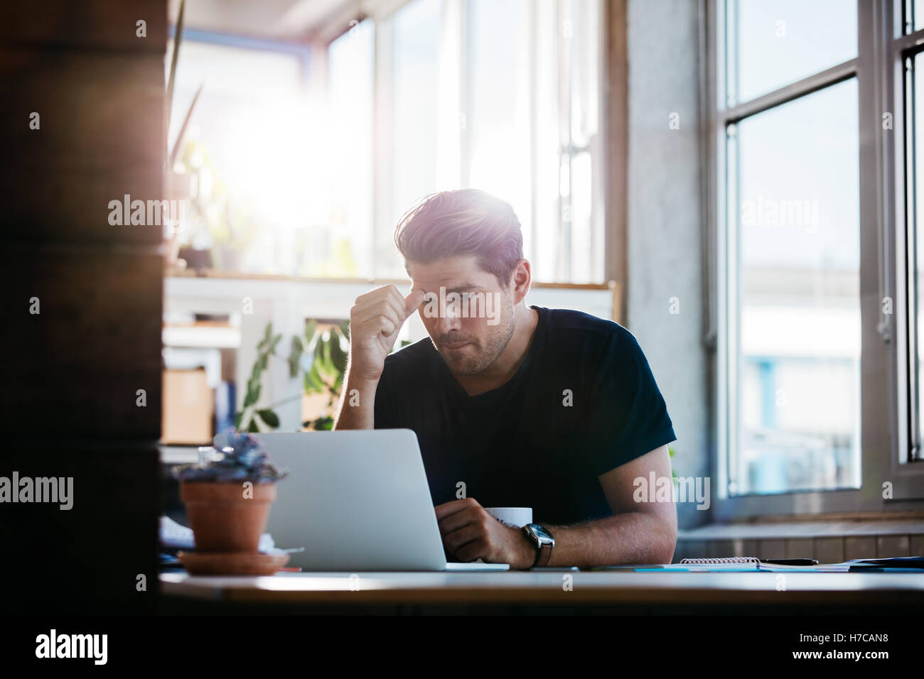 Young man working on the laptop in the office. Business man thinking about a problem at his computer. Stock Photo