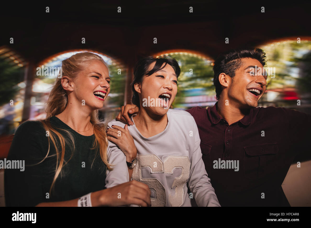 Group of friends on amusement park ride. Young man and women having fun together. Stock Photo
