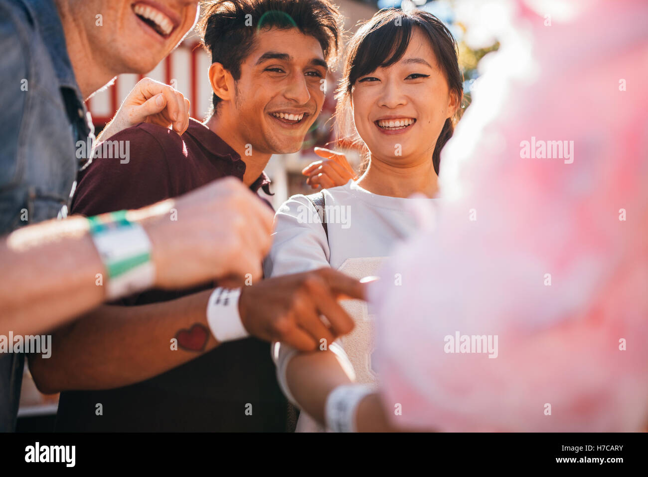 Friends with cotton candy outdoors. Young man and women sharing cotton candyfloss. Stock Photo