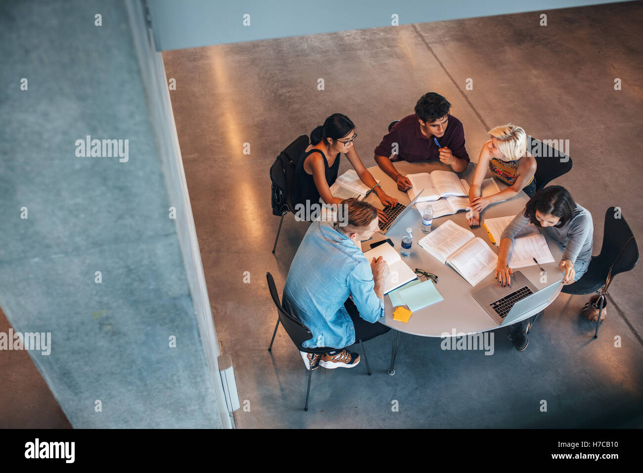 Multiethnic group of young people studying together at a table. Young students in cooperation with their school assignment. Stock Photo
