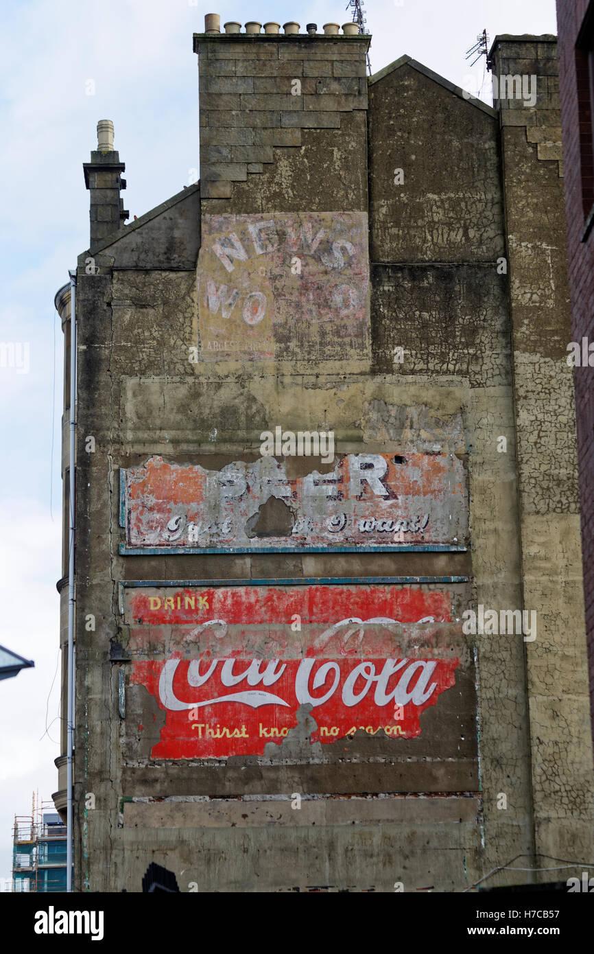 Old vintage advertising signs on the side of tenement building coke  coca cola news of the world and beer Stock Photo
