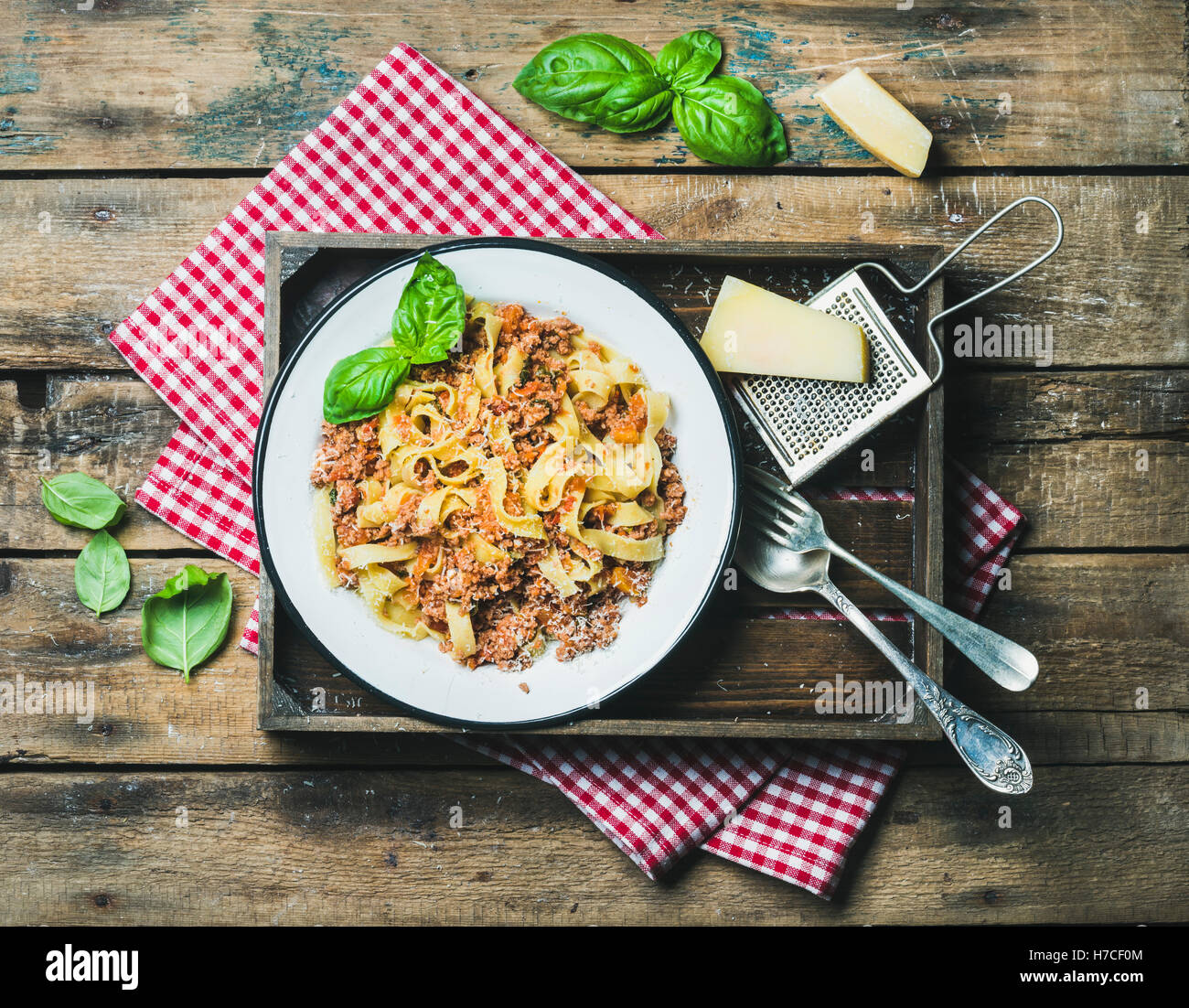 Italian pasta dinner. Tagliatelle Bolognese with Parmesan cheese and fresh basil in wooden tray over rustic wooden background, t Stock Photo