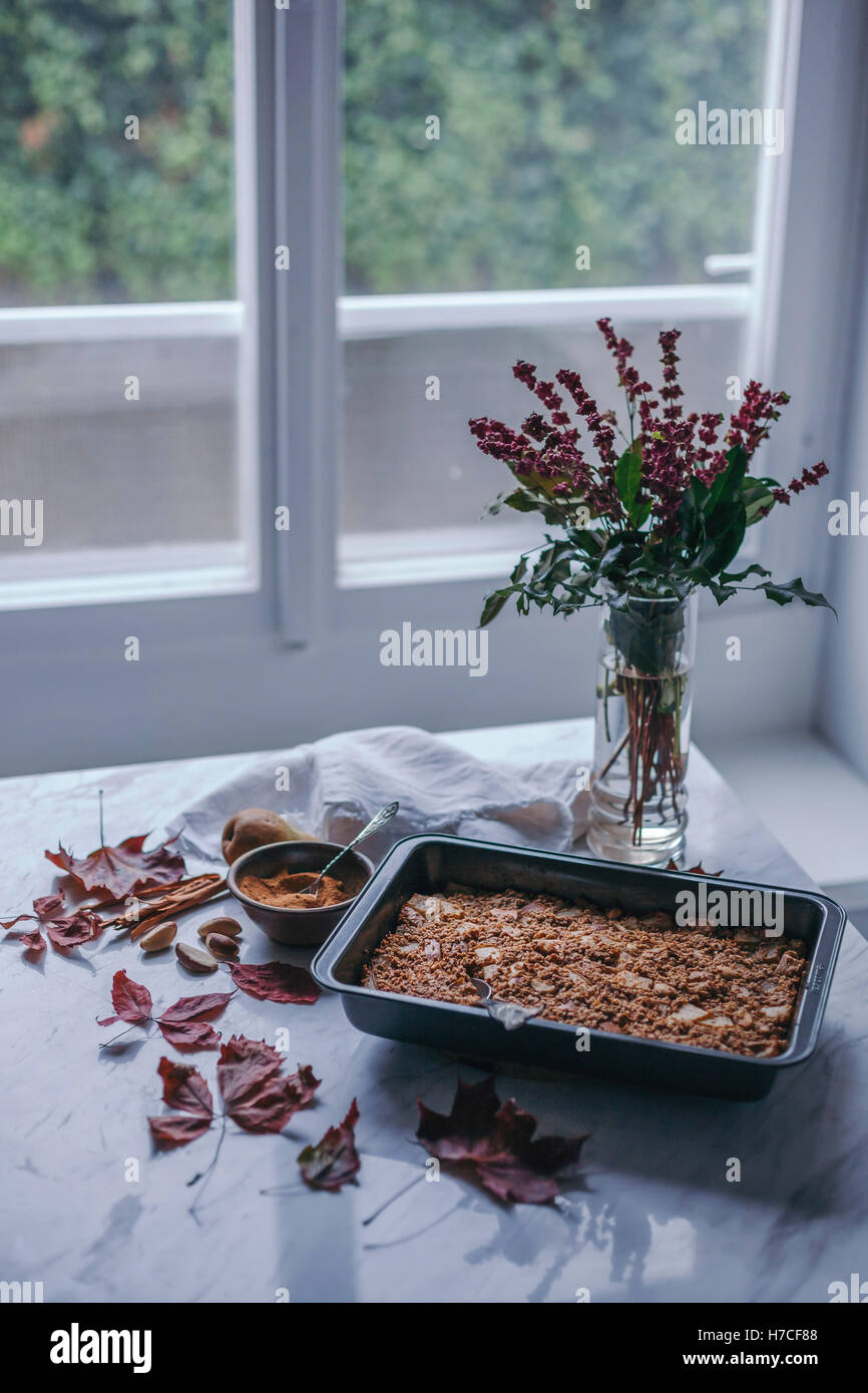 Pear and cinnamon baked oatmeal in a baking pan and coconut sugar in a bowl on white marble table Stock Photo