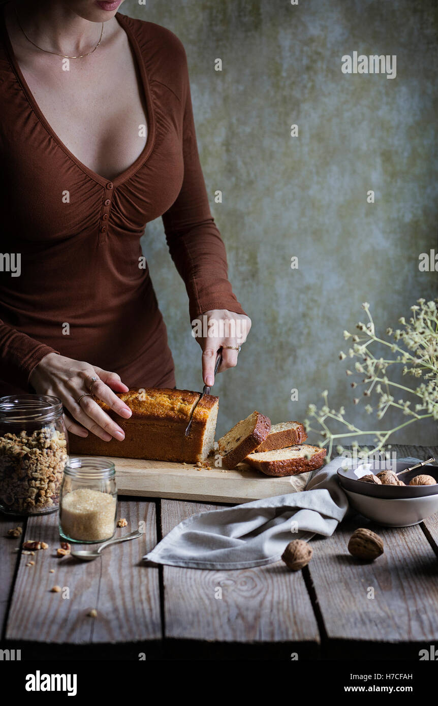 Woman cutting a cake on rustic wooden table Stock Photo