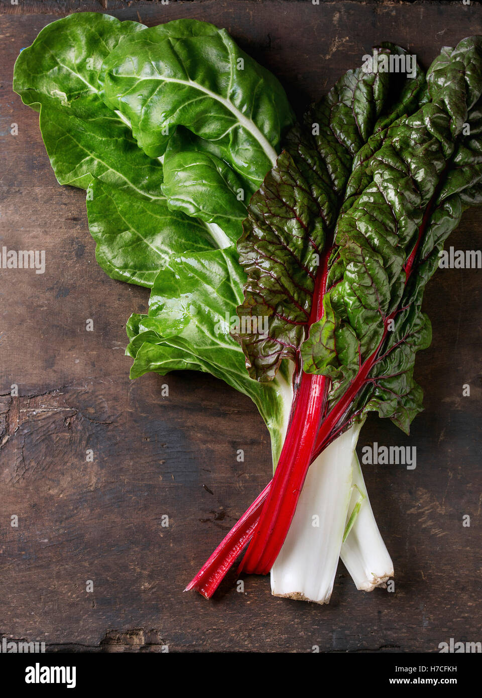 Variety of fresh chard mangold salad leaves over old dark wooden background. Top view with space for text. Healthy eating theme. Stock Photo