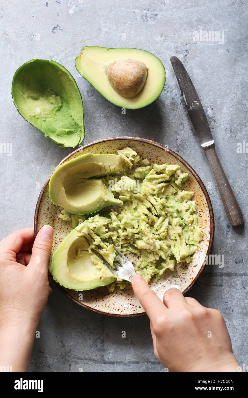 Mashing avocado for guacamole in a  bowl.Top view Stock Photo