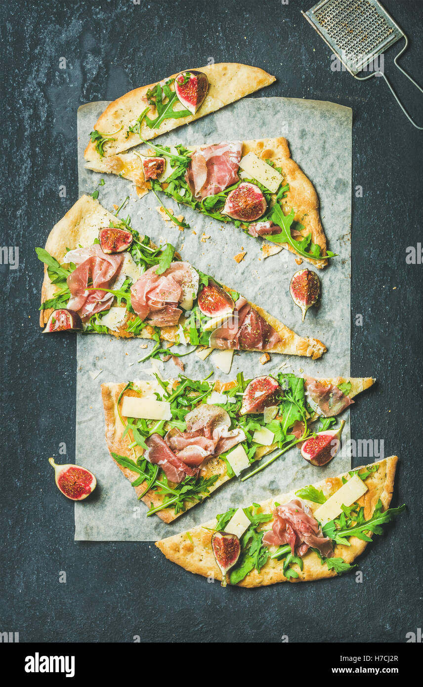 Fig, prosciutto, arugula and sage flatbread pizza on dark background