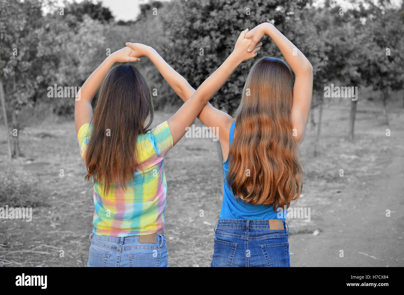 Best Friends Forever - two 12 year old teenage girls  holding hands in an infinity forever sign to signify BFF - color over blac Stock Photo