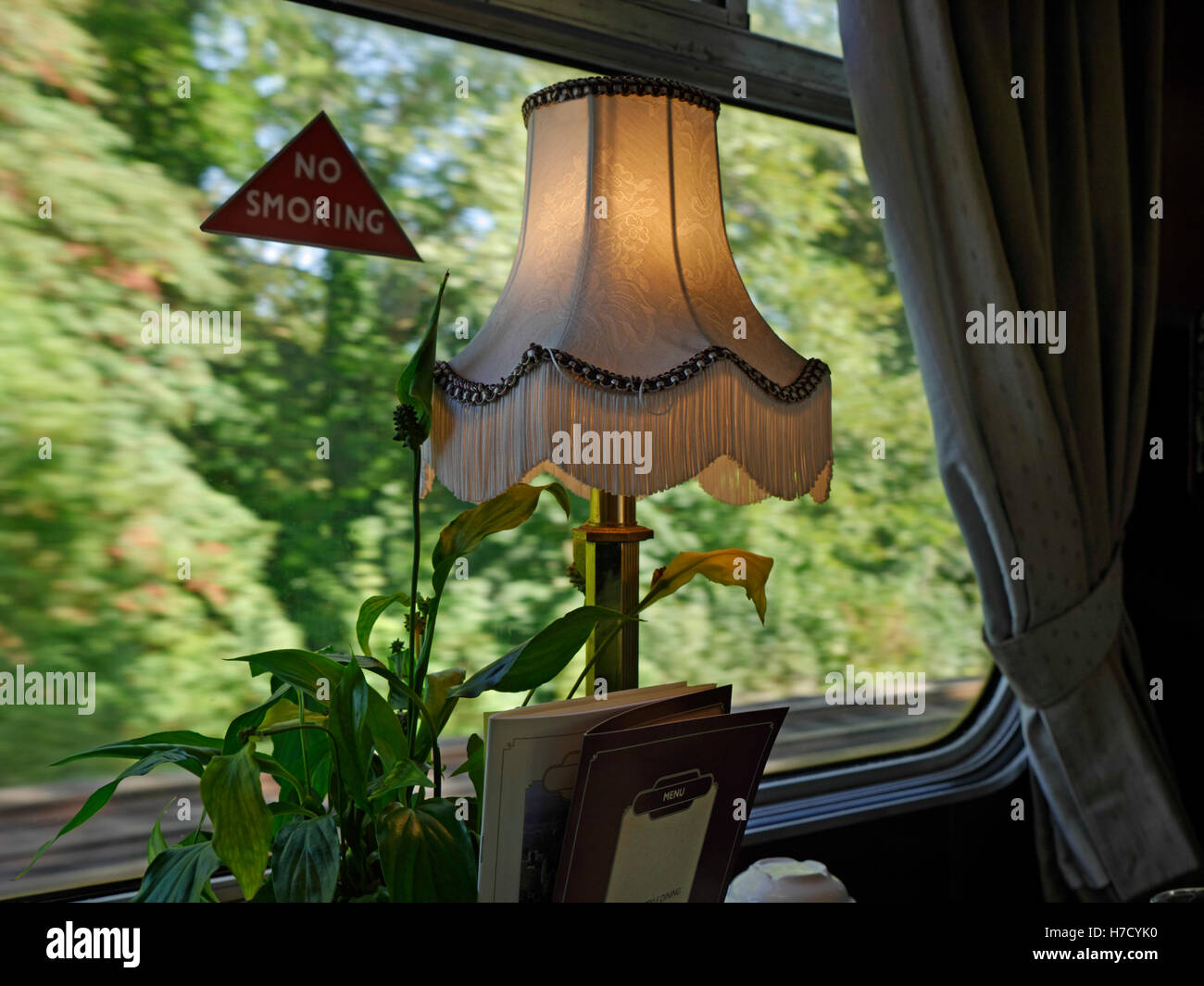 Pullman first class rail travel compartment with old style lamp on dining table with menus and speed blurred background Stock Photo