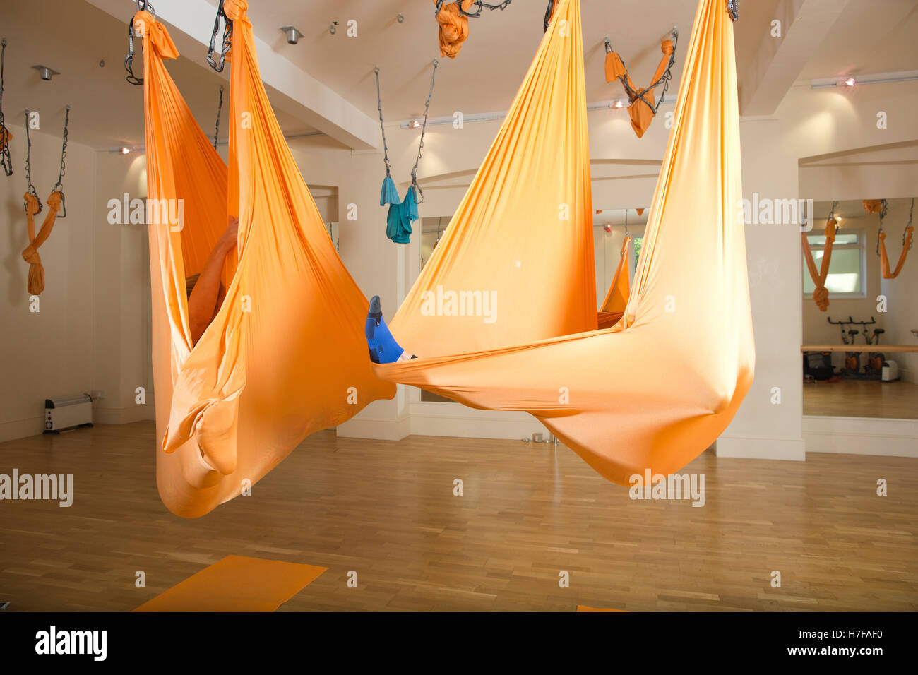 Man taking part in Aerial Yoga class with woman instructor