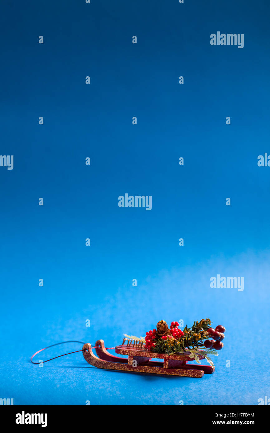 Christmas card in vertical orientation with decorative sledge standing on blue background. Stock Photo