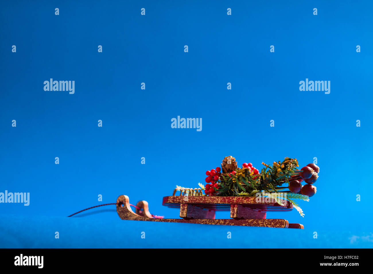 Christmas card with decorative sledge standing on blue background. Stock Photo